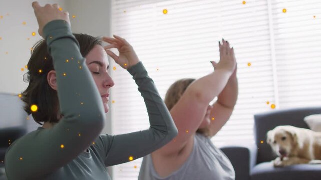 Two women sitting, raising arms on inhale, gold particles appearing, settling into mudras for yoga