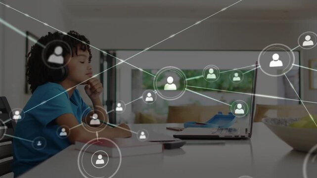 Schoolboy wearing headset home watching laptop as user icon expanding forming education network