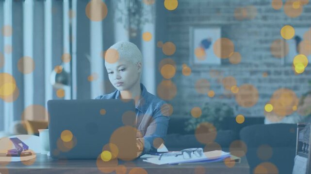 Adult female starting by typing at laptop for remote work, reviewing papers as bokeh overlay drifts