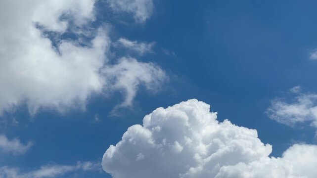 Cloudscape Symphony: A captivating view of the sky, featuring fluffy, white clouds floating against a vibrant blue canvas, creating a sense of peace and serenity.
