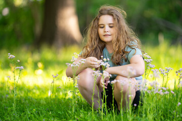 Naklejka premium Wildflowers surround smiling child outdoors. Summer wildflowers create scenic background. Wildflowers add cheerful spring mood. Wildflowers portrait feels bright and joyful.