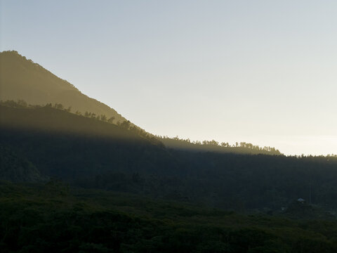 Aerial view of Bunker Kaliadem Merapi area with golden sunlight hitting the mountain ridge and dense forest below Kecamatan Pakem, Daerah Istimewa Yogya, Indonesia.