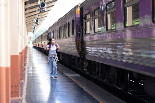 Woman traveler carrying a backpack running alongside a moving train on a station platform, highlighting concepts of travel, urgency, and transportation.