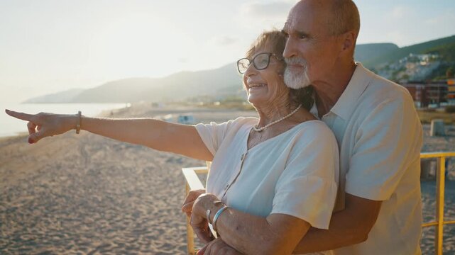 Elderly couple in their seventies enjoying a romantic moment together on the beach, watching the sunset from a lifeguard tower, sharing happiness and love during their summer vacation