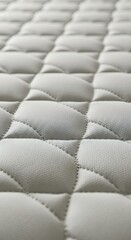 Fototapeta premium Light colored quilted textile surface shows repeating diamond pattern with fine texture