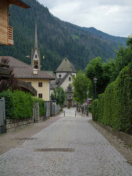 A Mountain Town Road Leads To Moena Church with Bell Tower - Italy