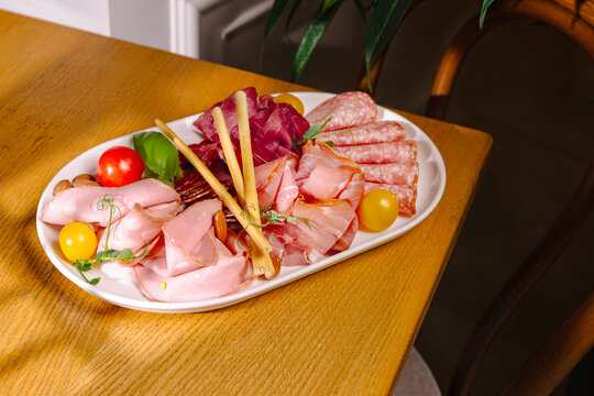 Platter of assorted meats and vegetables on a wooden table displayed in a home