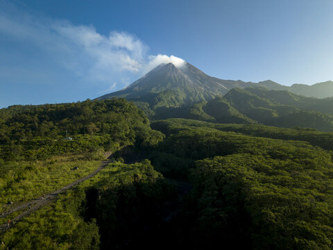 Aerial view of Mount Merapi volcano with smoke rising from the crater above the lush green forests of Bunker Kaliadem Kecamatan Pakem, Daerah Istimewa Yogya, Indonesia.