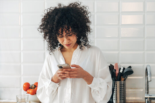 Woman enjoying kitchen time, communicating using smartphone