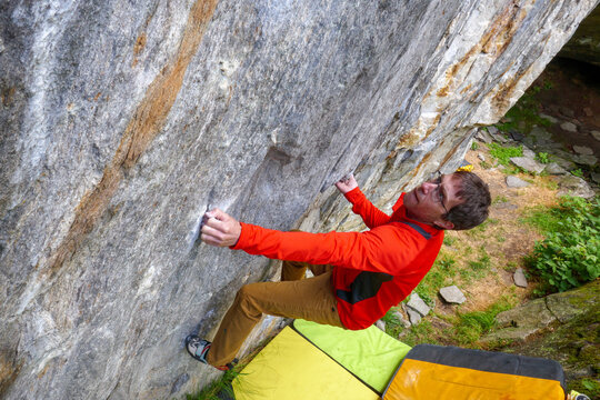 Giovane uomo pratica bouldering. Arrampicata su massi