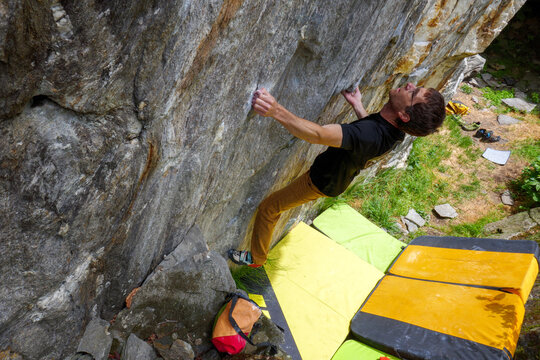 Giovane uomo pratica bouldering. Arrampicata su massi