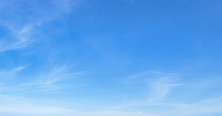 Clear blue sky with wispy clouds drifting gently. Soft gradients from deep to pale blue dominate the frame © lovelyday12