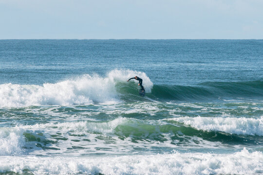 Surfer in a wetsuit riding a breaking wave, performing an active sport