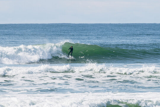 Young man in wetsuit surfing a green breaking wave in the sea