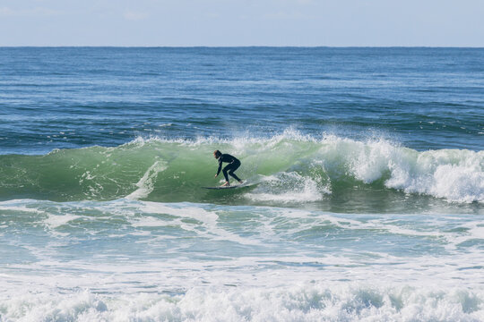 Surfer riding green ocean wave in wetsuit