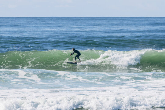 Surfer riding ocean wave in wetsuit
