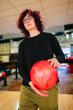 Teen age girl at bowling holding red ball in indoor alley