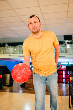 Man at bowling holding red ball in indoor alley