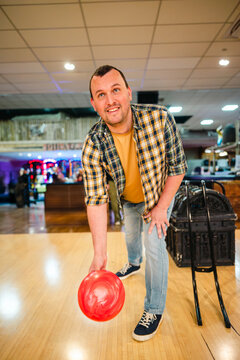 Man bowling with red ball in indoor alley