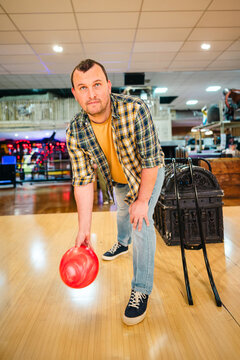 Man bowling with red ball in indoor alley