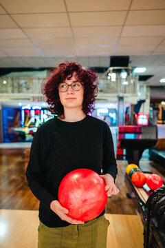 Teen age girl at bowling holding red ball in indoor alley