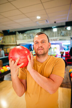 Man at bowling holding red ball in indoor alley