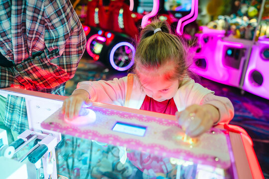 Young girl playing arcade game with colourful lights