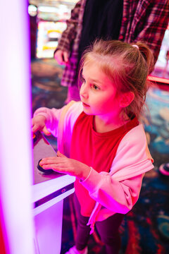 Young girl playing arcade game with colourful lights