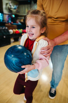 Little girl with father, at bowling in indoor alley