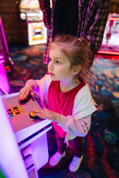Young girl playing arcade game with colorful lights