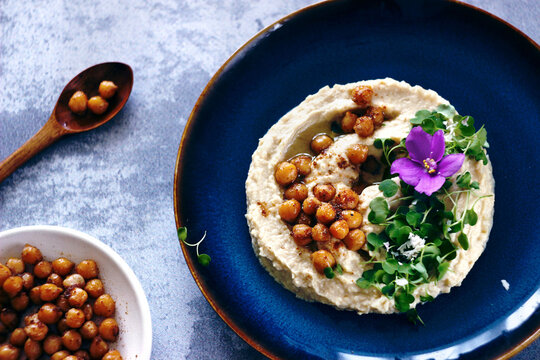 Hummus with arugula microgreens, chickpeas and violet flowers