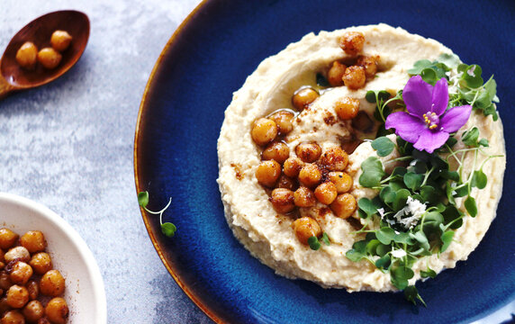 Hummus with arugula microgreens, chickpeas and violet flowers