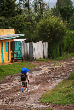 Young child walking alone on muddy rural road