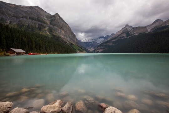 Turquoise Mountain Lake With Cabin, Forest and Glacier Under Moo