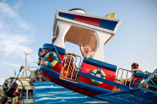 Child waving excitedly on carnival boat ride