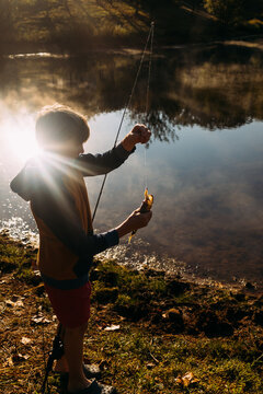 Child holding bass fish lakeside in morning light