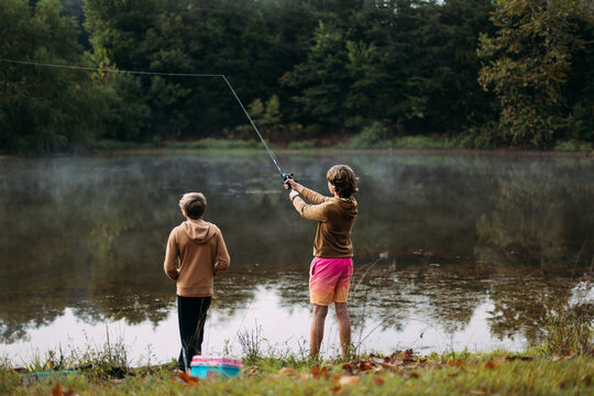 Kids fishing together on misty lake