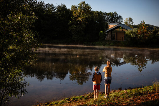 Boys fishing at sunrise lakeside with reflection