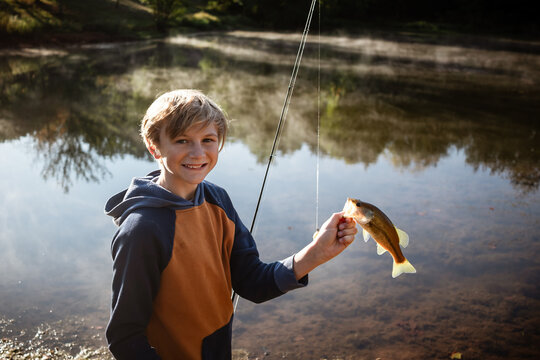 Boy holding fresh catch by lakeshore