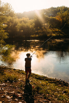 Silhouette child casting line at golden hour