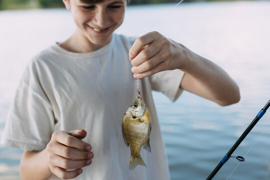 Preteen boy proudly holding up catch while fishing