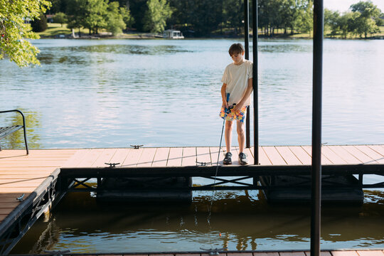 Boy Fishing From Lakeside Dock