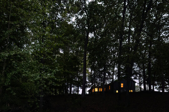 Cabin Lights Glowing Through Forest Trees