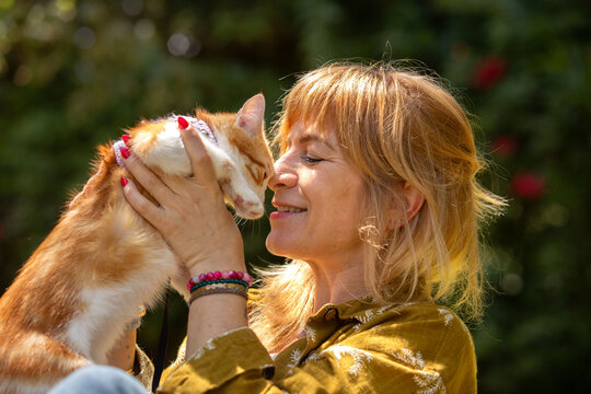 Happy woman bonding with her ginger cat in sunlight