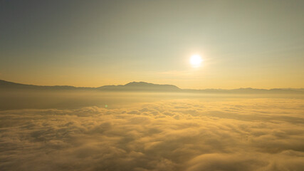 A breathtaking sunrise view above a vast sea of clouds with distant mountain silhouettes under a clear blue sky. Perfect for themes of tranquility, nature, and atmospheric landscapes. © Narong Niemhom