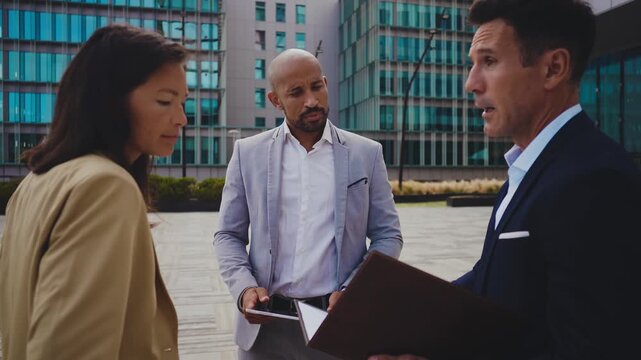 Business people meeting in a business park - Corporate businessmen and businesswoman bonding outdoors, colleagues meeting after work.
