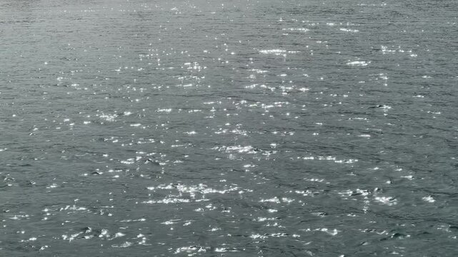 Close-up view of the sea with small waves and sunlight shimmering on the water surface. Calm ocean scenery with sparkling highlights. Tranquil summer seascape