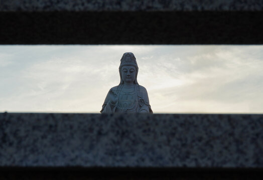 Guan Yin statue at a Chinese temple viewed through a symmetrical stone gap.