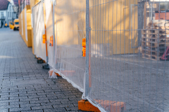Temporary construction fencing installed along a city sidewalk at an urban building site. Industrial safety and infrastructure development concept highlighting renovation and municipal work in