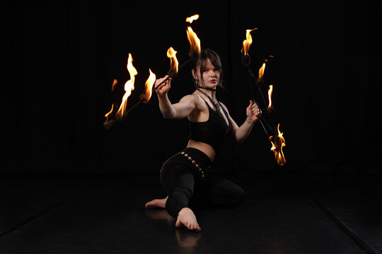 Dark fire performance with elegant woman holding flames